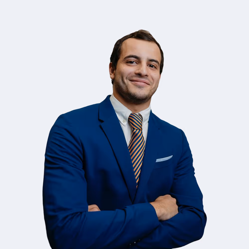 Confident man in a blue suit with striped tie, smiling with arms crossed.