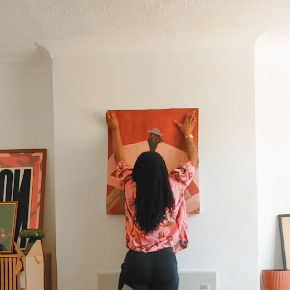 Kei holding up a Studio Imo illustration in the middle of the room.