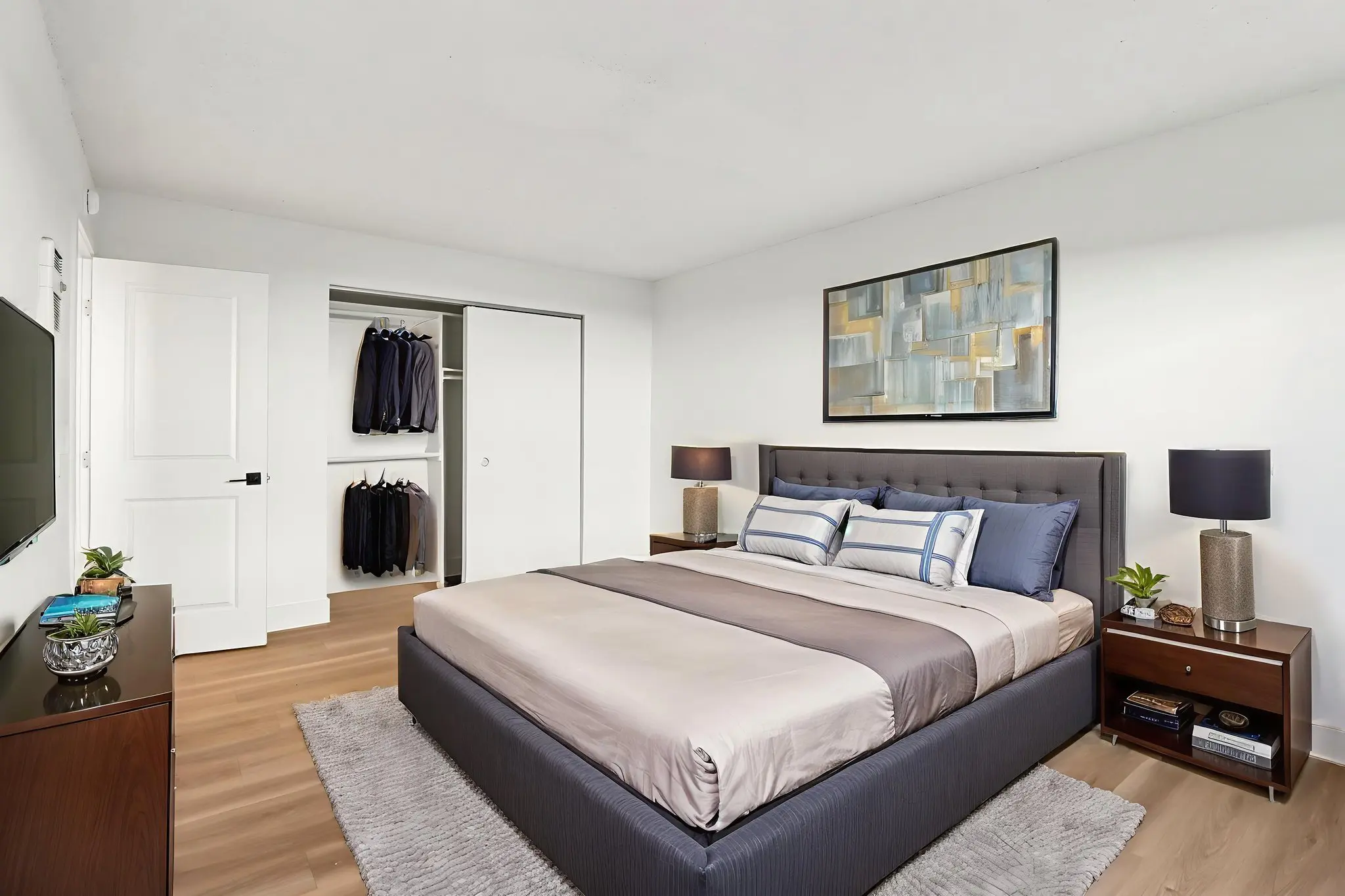 Bedroom with bed, bedside table with lamp and tv with closet