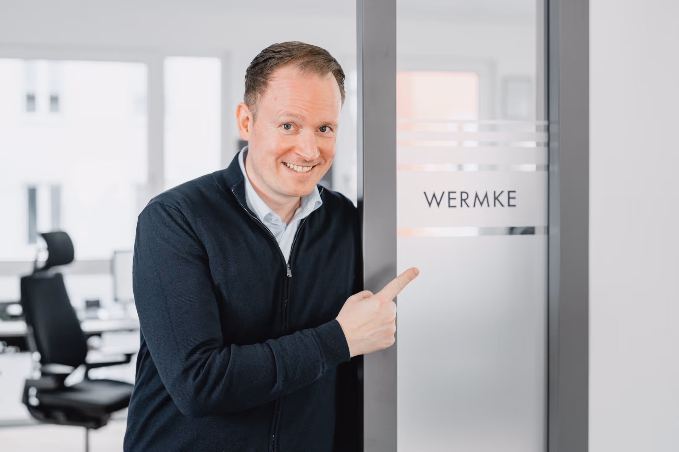 Christian Wermke deutet auf seinen Namen an seinem Büro