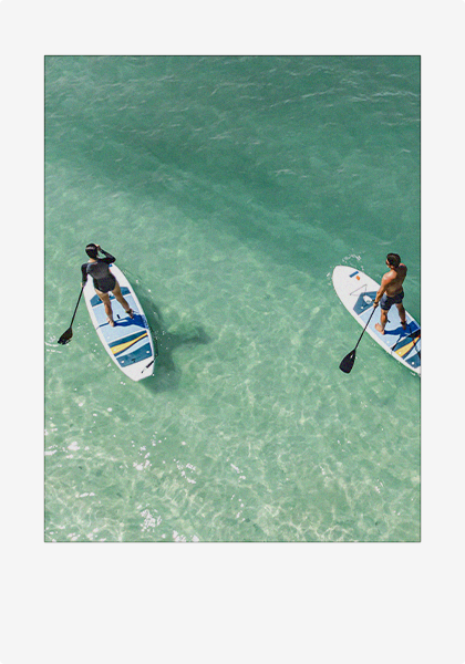 A polaroid picture of a couple paddle-boarding in the ocean.