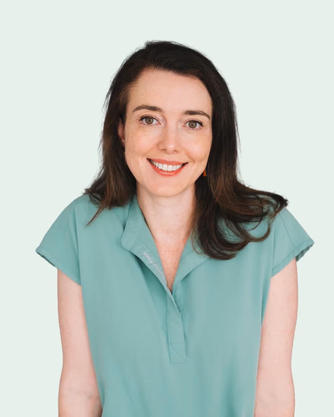 A woman in a green shirt smiles at the camera.
