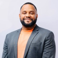 A headshot of a black man wearing a suit and shirt