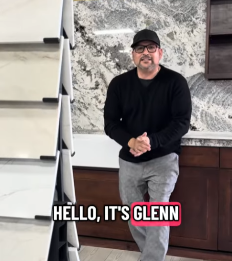 Glenn Guiterrez wearing glasses, a black cap and black sweater standing in a kitchen showroom with marble countertops and cabinets, with text 'Hello, it's Glenn' at the bottom.