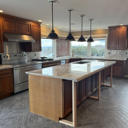 Kitchen renovation in progress with new Taj Mahal granite countertops and updated backsplash installed, waterfall edge not yet completed