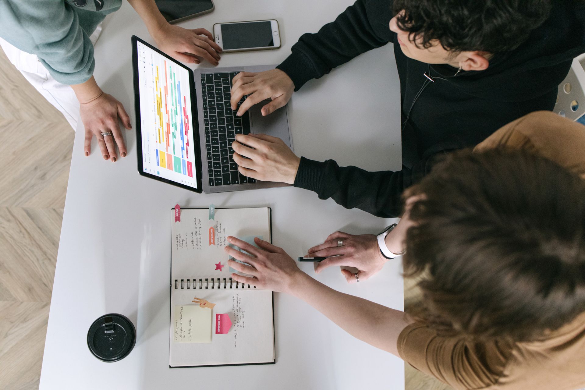 A high-angle view of a team collaborating over a laptop and notebook in a modern office.
