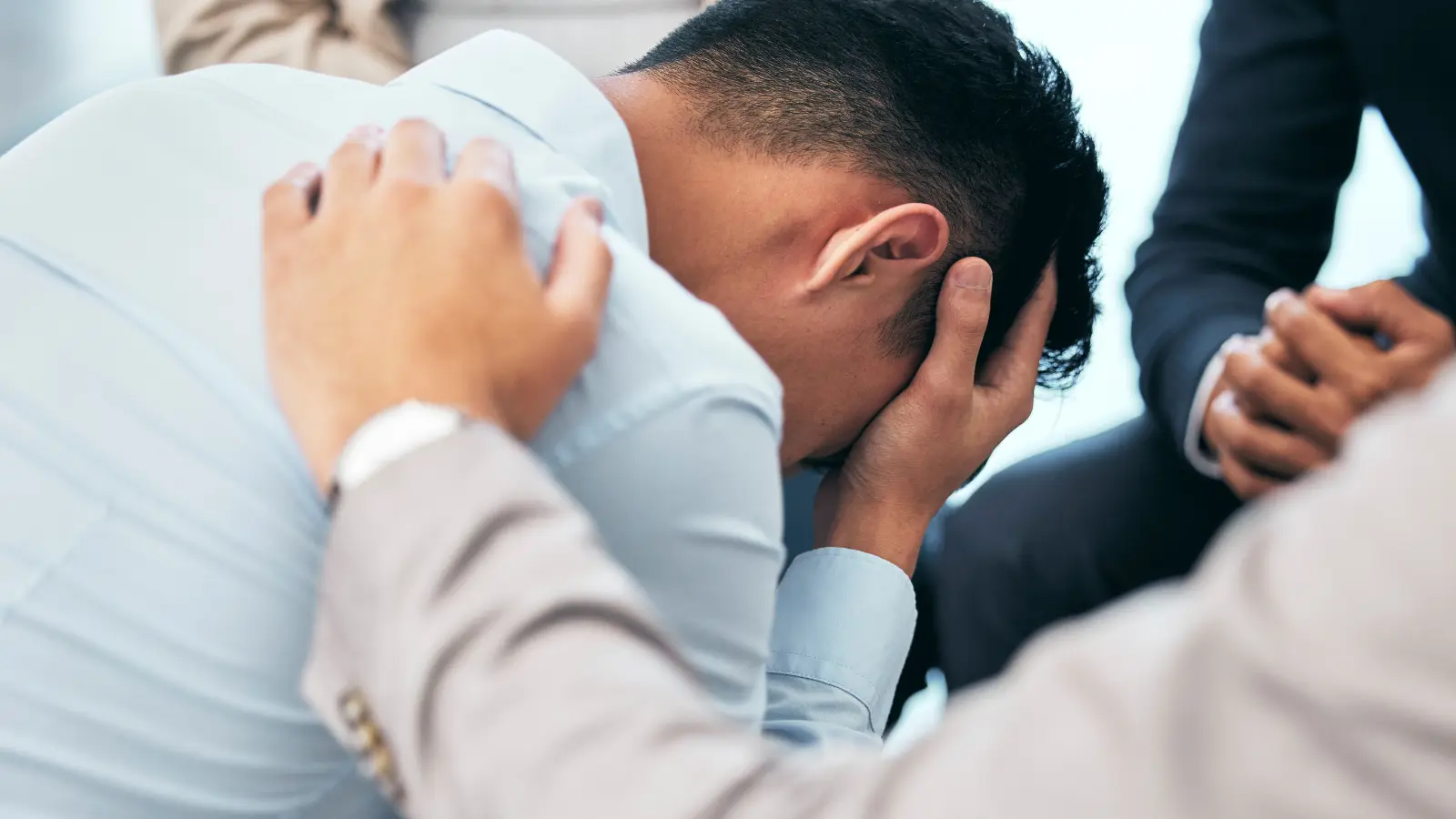 Hands comforting distressed man in office