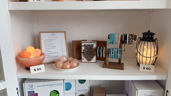 Shelf displaying Himalayan salt lamps, beaded bracelets on wooden stands, and a framed owl artwork.