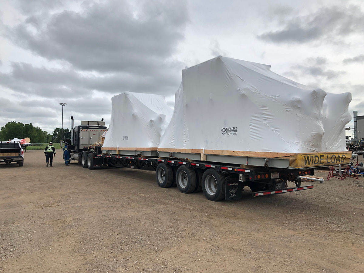 Carriers team wrapping process equipment at a coastal industrial site