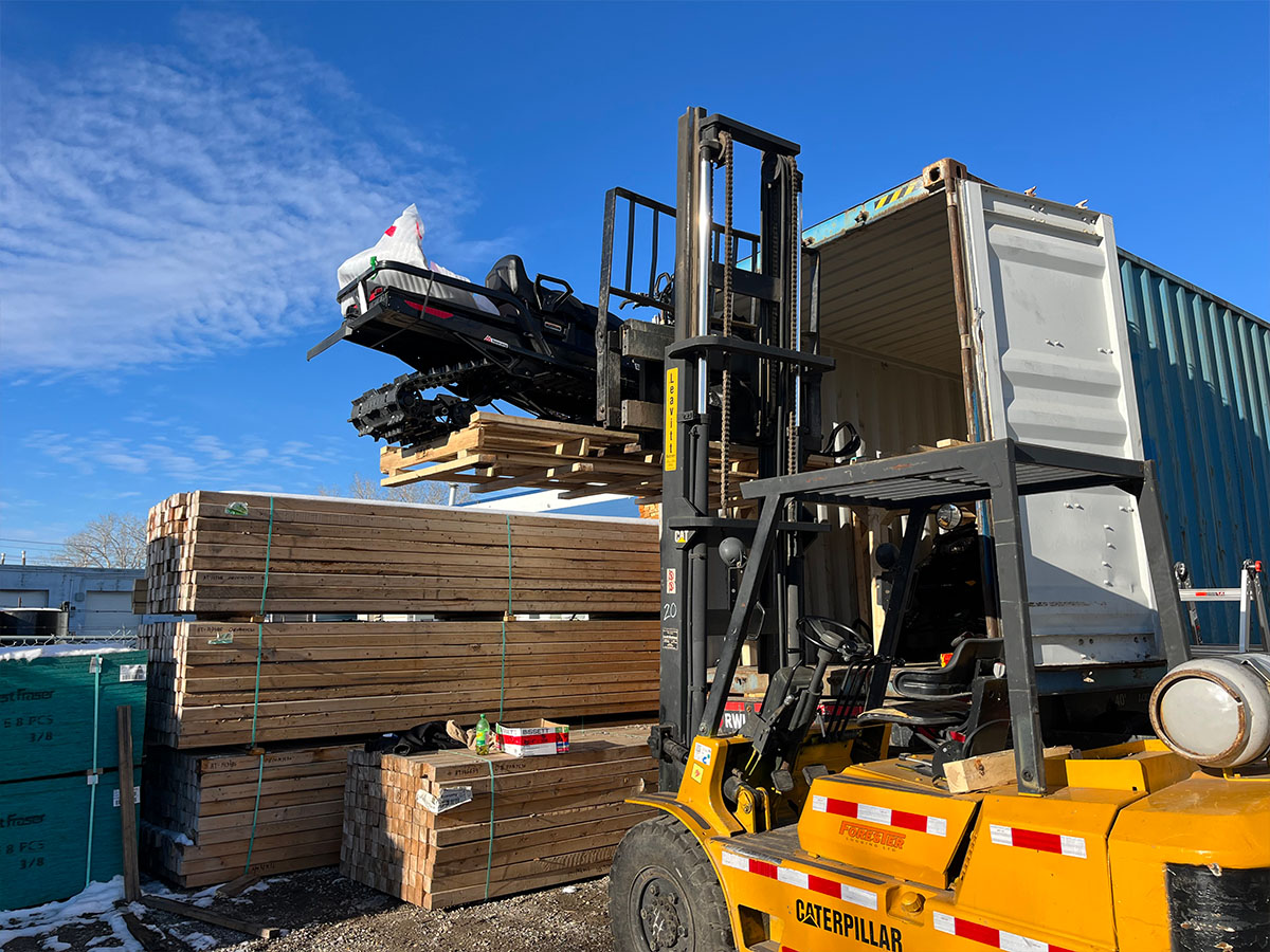 Container loading team positioning heavy machinery for export shipment