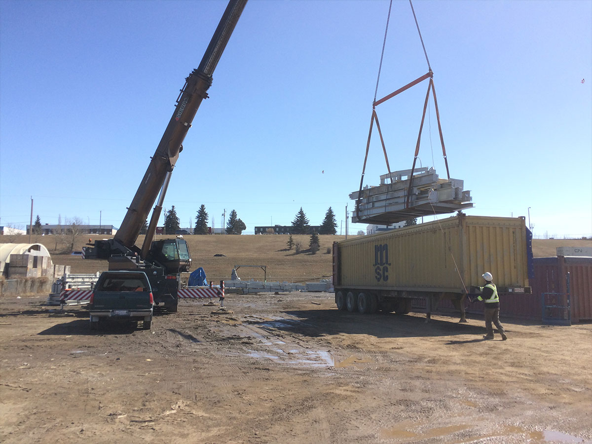 Container loading crew securing tall machinery with overhead bracing
