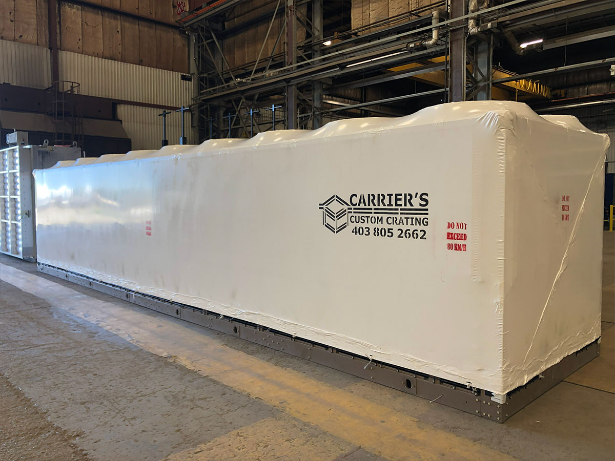 Shrink-wrapped equipment on an open flatbed trailer for long-haul transport