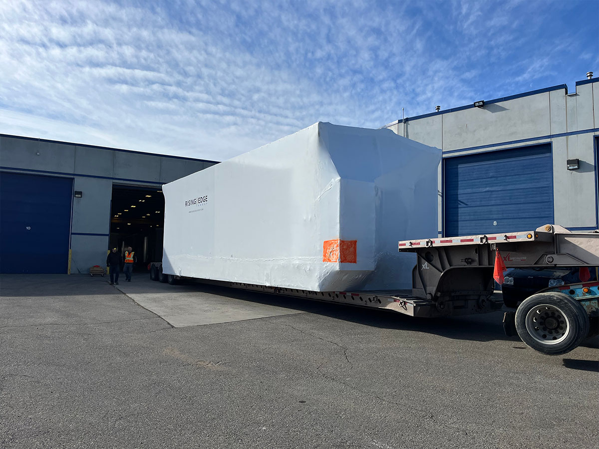 Industrial wrapping crew completing shrink wrap on large outdoor equipment