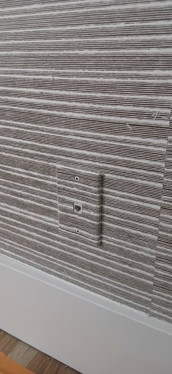 Wall with brown and white horizontal striped textured wallpaper and a matching textured light switch cover.