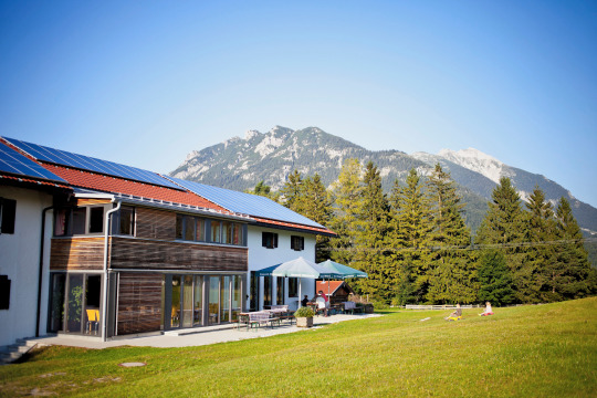HI Mittenwald youth hostel with wooden Alpine facade and Bavarian Alps mountain backdrop