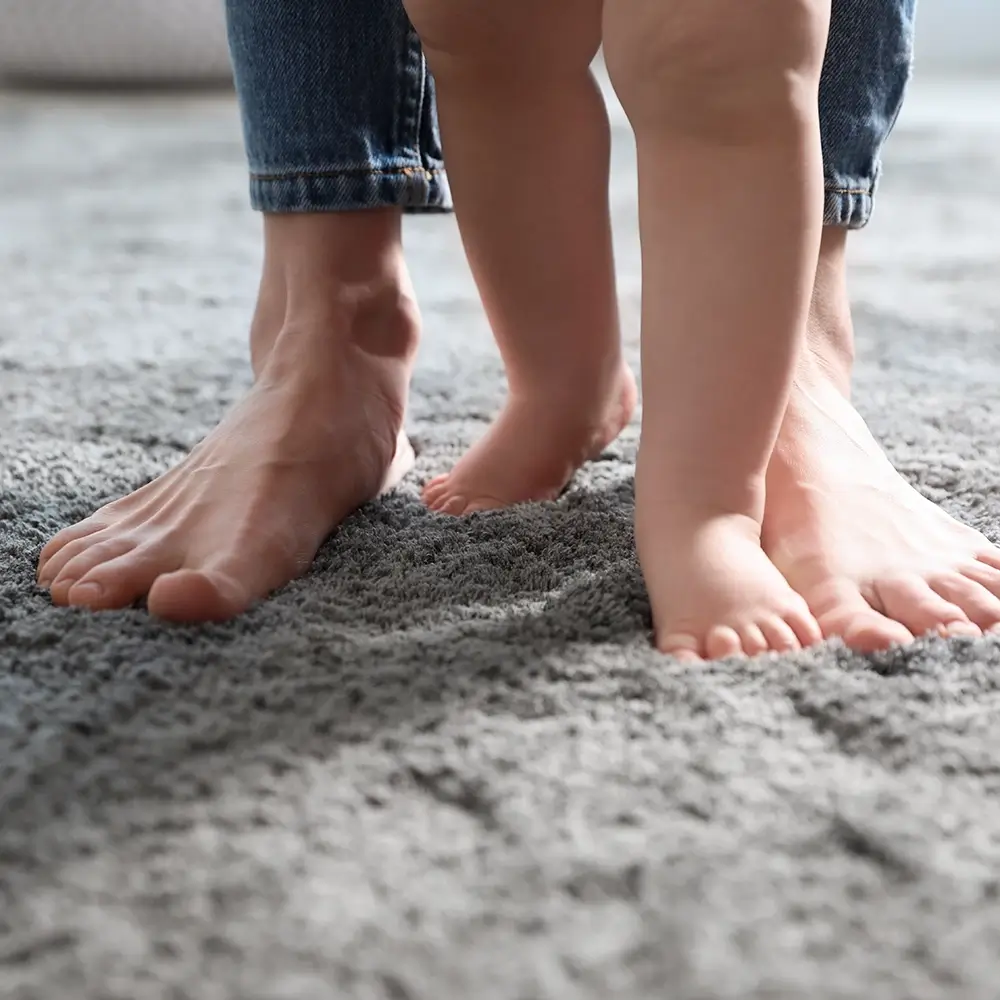 Dad and baby's feet walking across well padded flooring.