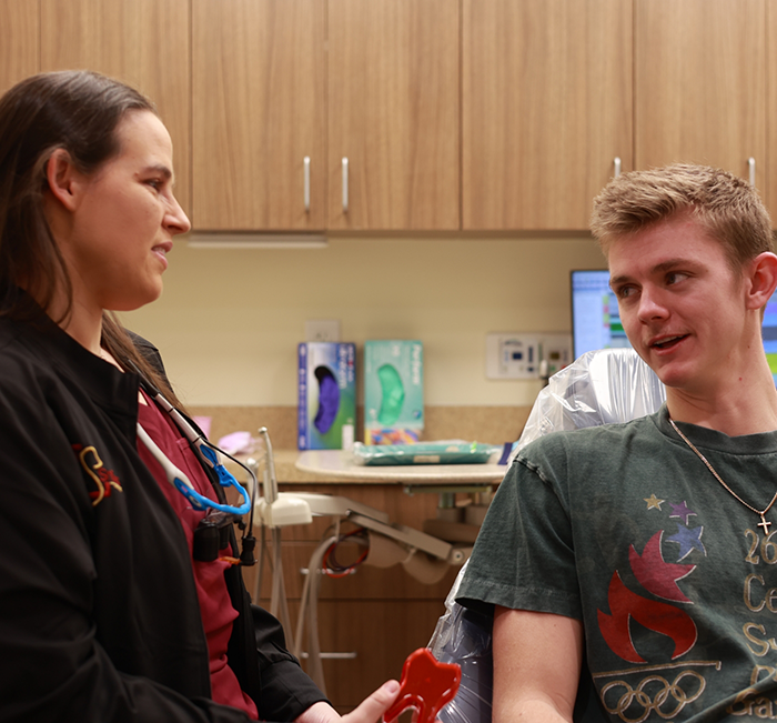 Dentist consulting with a young male patient seated in a dental chair during an exam