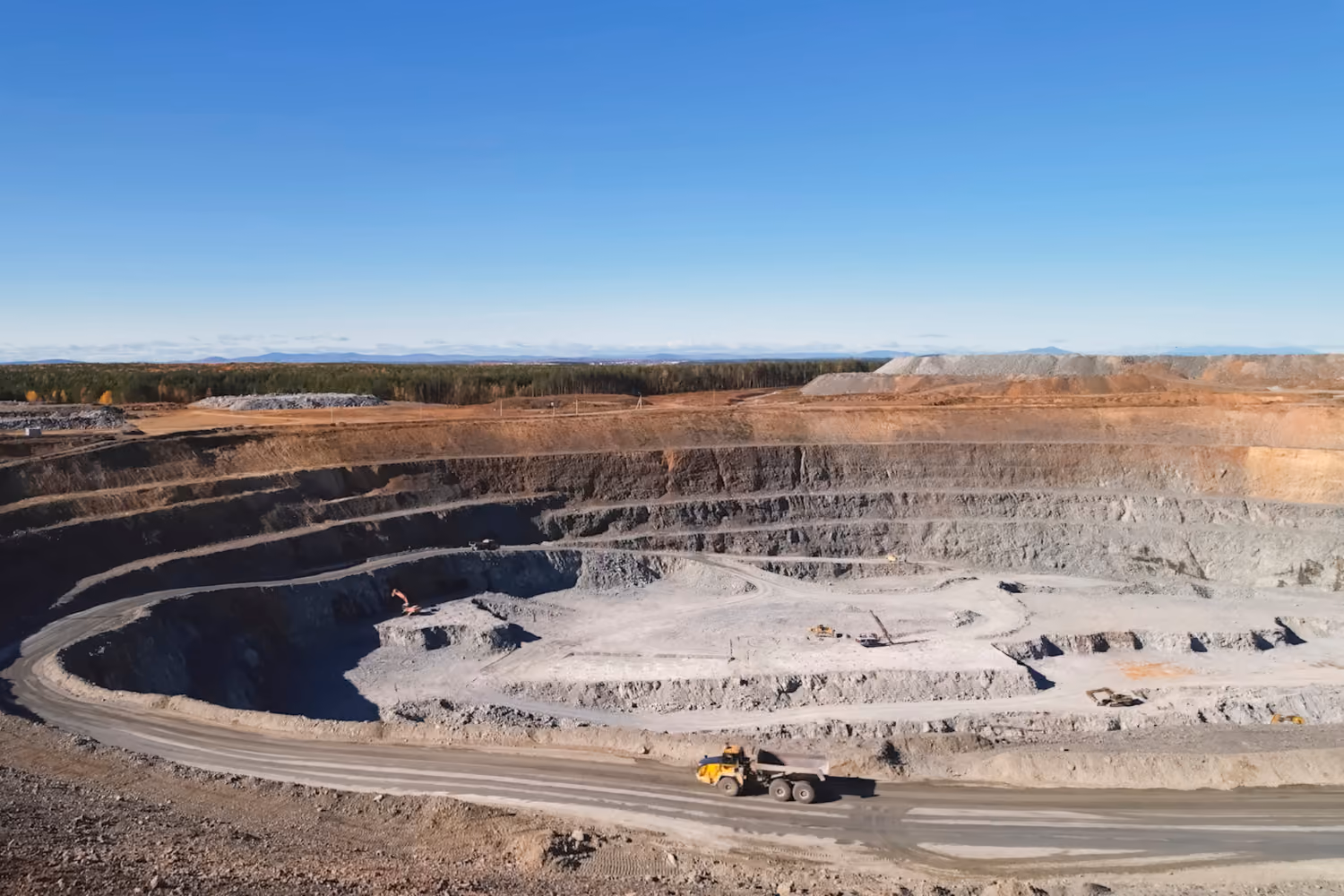 Open-cut mining operation with extraction benches and haul roads.