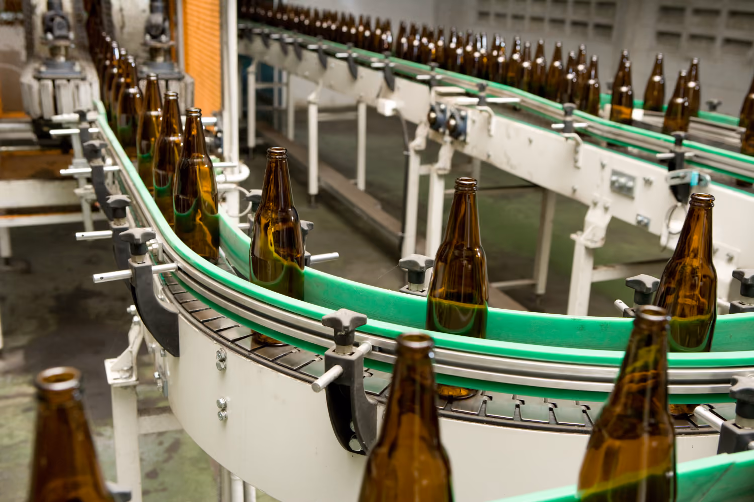 Beverage production line with bottles moving through an automated filling process.