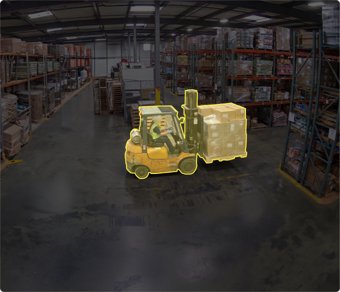 Aerial view of a yellow forklift carrying a pallet of boxes through a warehouse aisle, highlighted with a yellow safety outline to illustrate vehicle and equipment incident detection.
