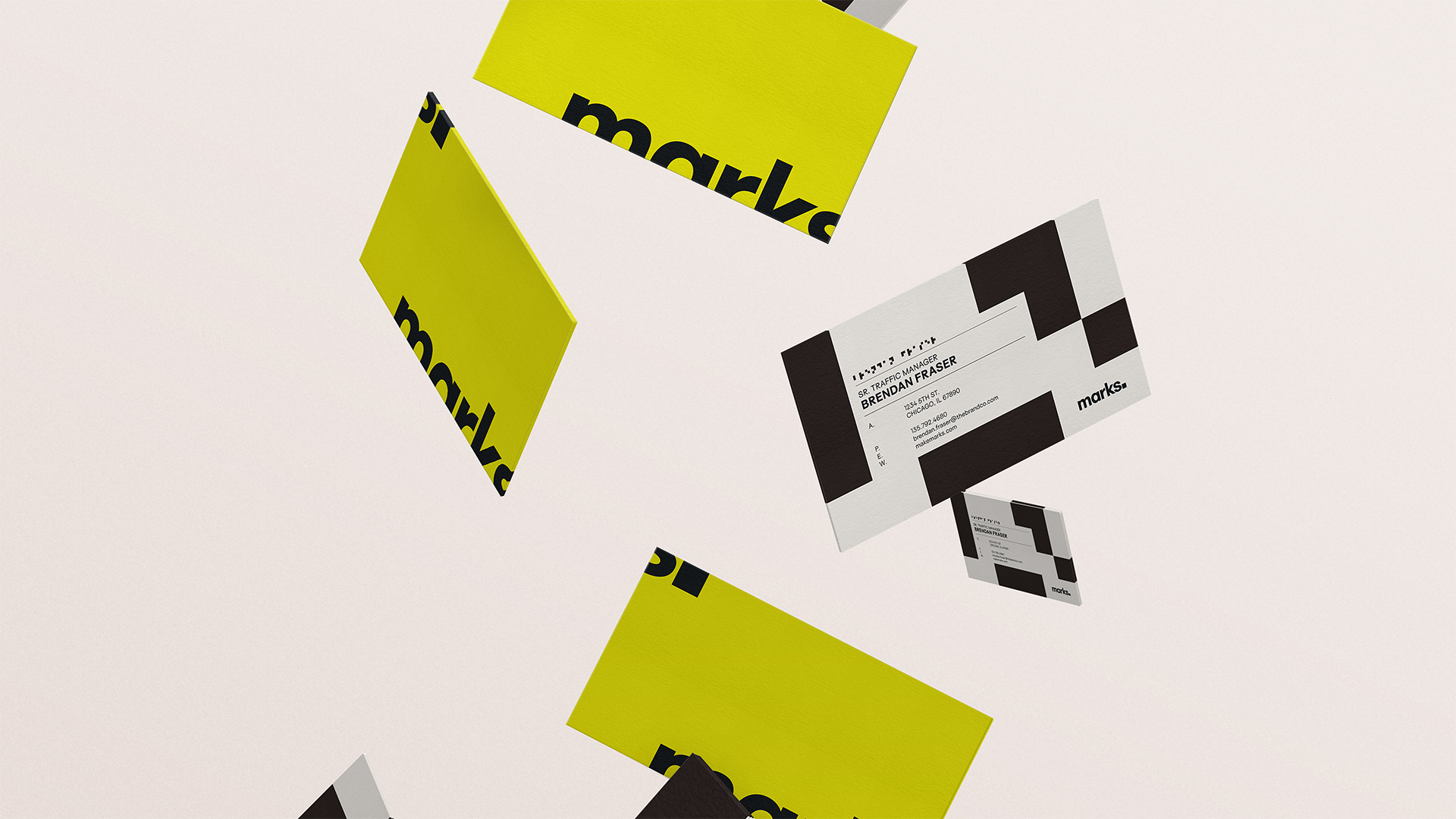 Floating business cards with black and white geometric patterns and bright yellow backs featuring the word 'marks.'
