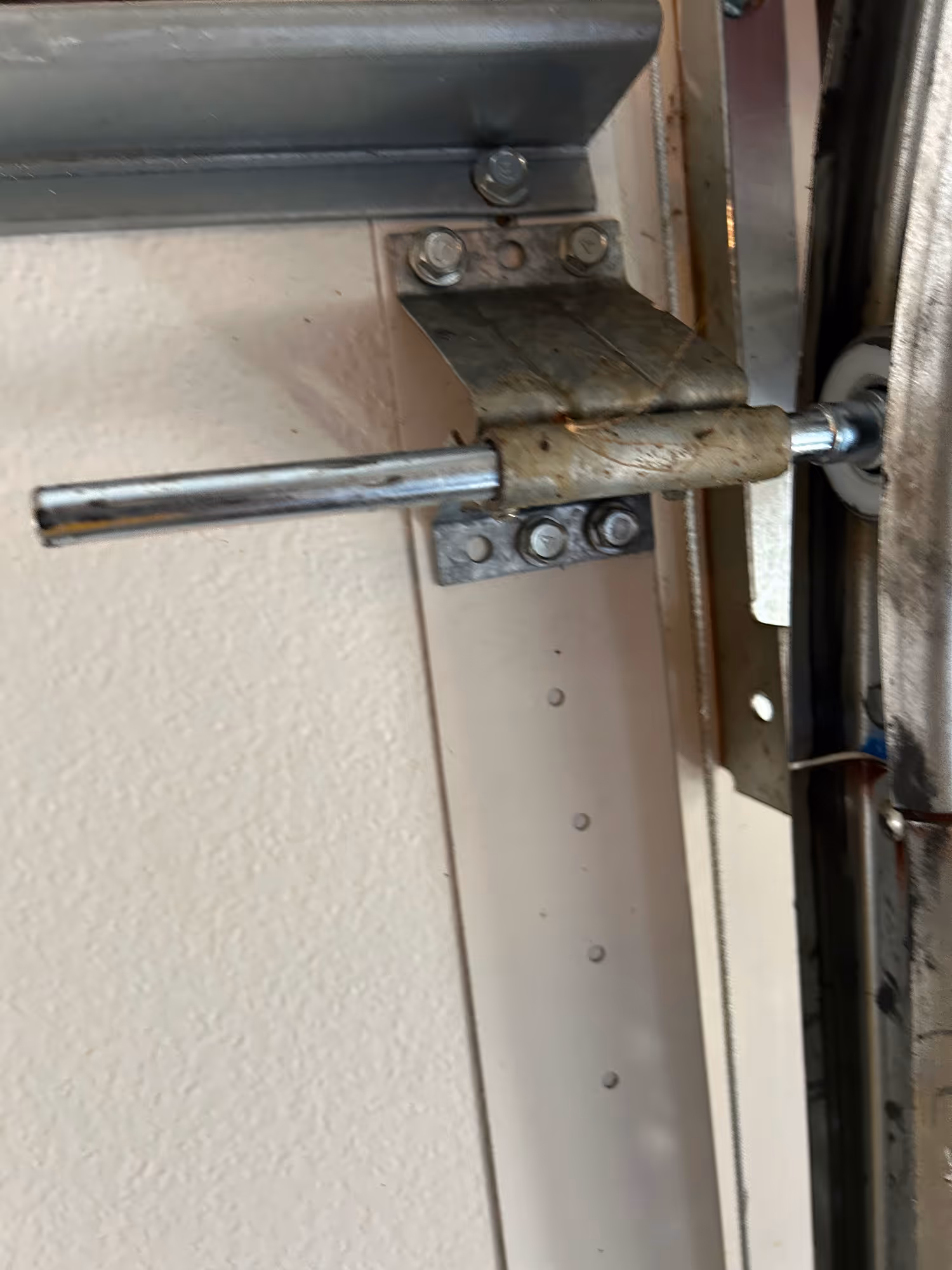 Close-up of a weathered metal garage door locking bar mechanism mounted on a wall.