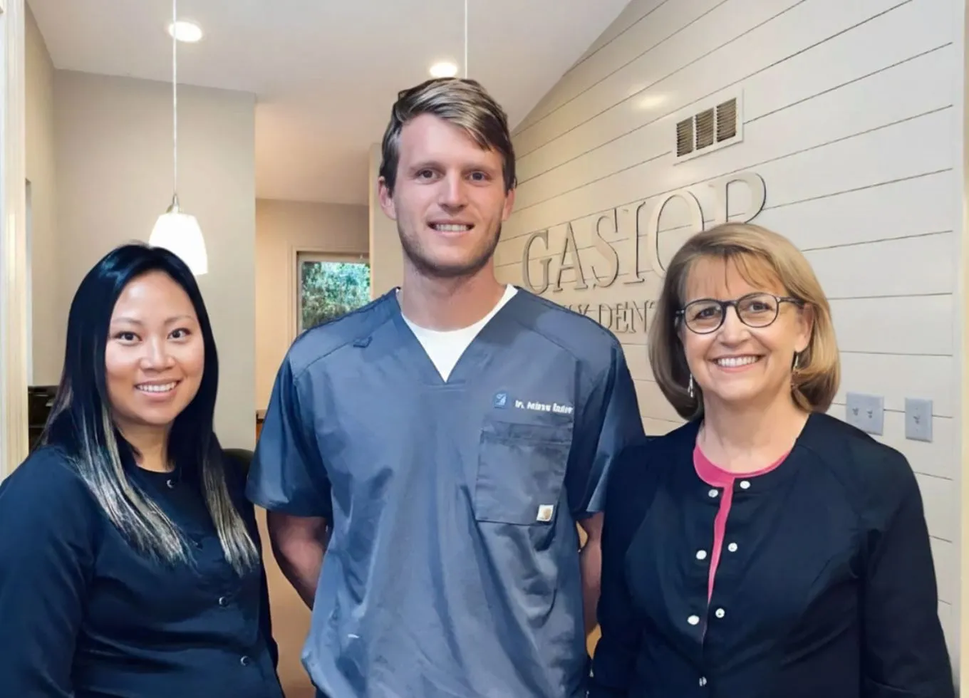 Group of smiling dental professionals standing together in an office hallway