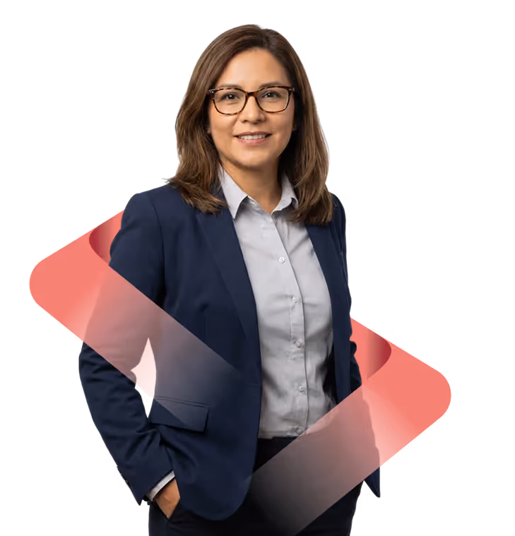 Smiling woman with glasses wearing a navy blazer and light blue shirt, standing with hands in pockets.