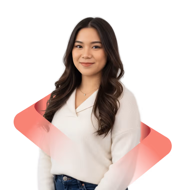 Portrait of a smiling young woman with long wavy hair wearing a white sweater and jeans, with a pink translucent diagonal ribbon behind her.