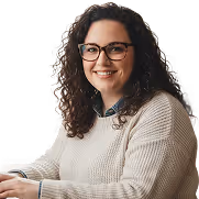 Smiling woman with curly hair and glasses wearing a light beige sweater.