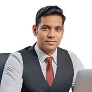 Professional young man in white shirt, red tie, and black vest seated in front of a laptop.