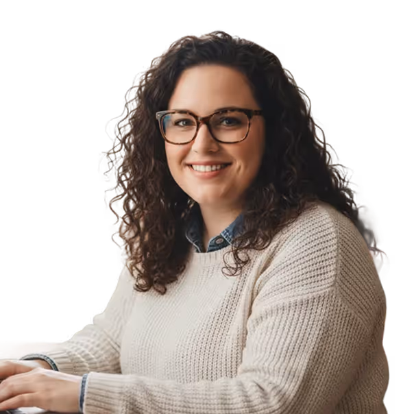 Smiling woman with curly brown hair and glasses wearing a cream knit sweater.