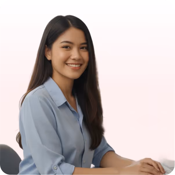 Smiling woman with long dark hair wearing a light blue shirt sitting at a desk.