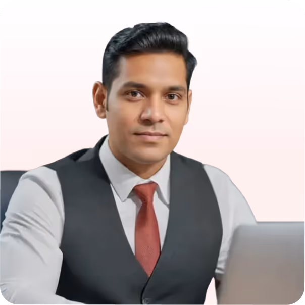Professional man in a white shirt, red tie, and black vest sitting at a desk with a laptop.