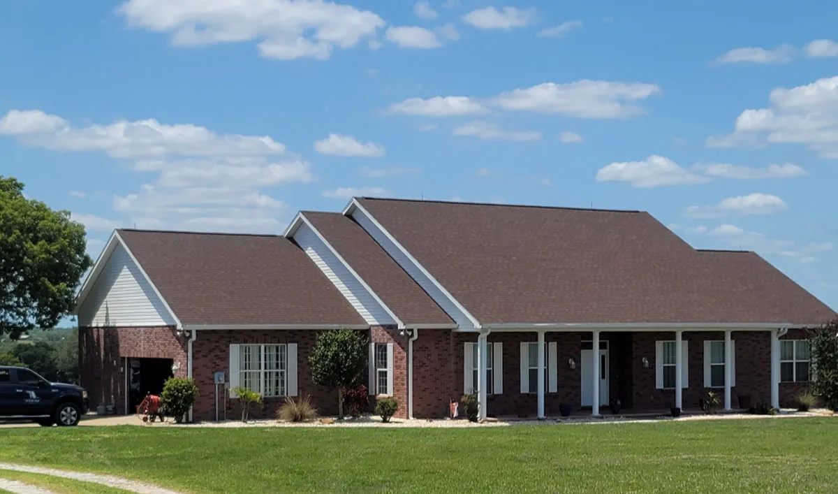 Completed brick ranch-style home with new shingle roof and covered front porch built by Florida building contractor