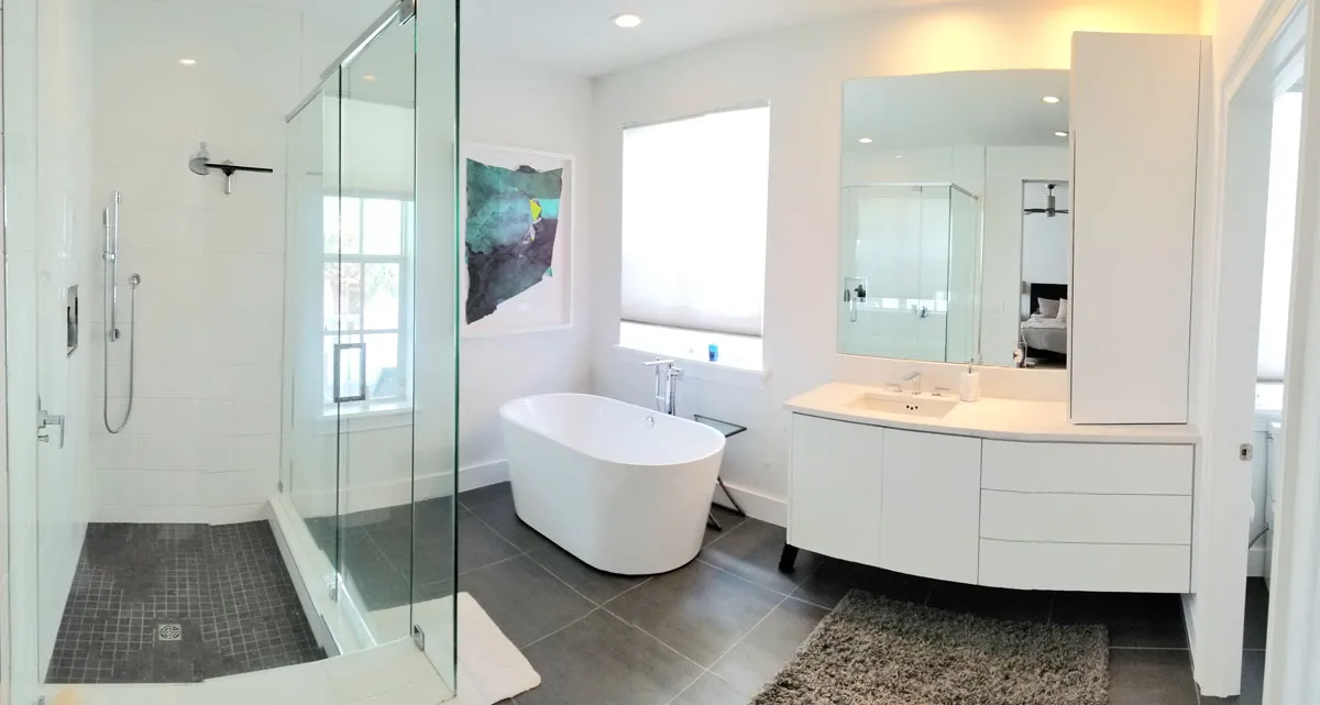 Spa-inspired master bathroom by Florida building contractor with frameless glass shower, freestanding tub, and modern curved floating vanity