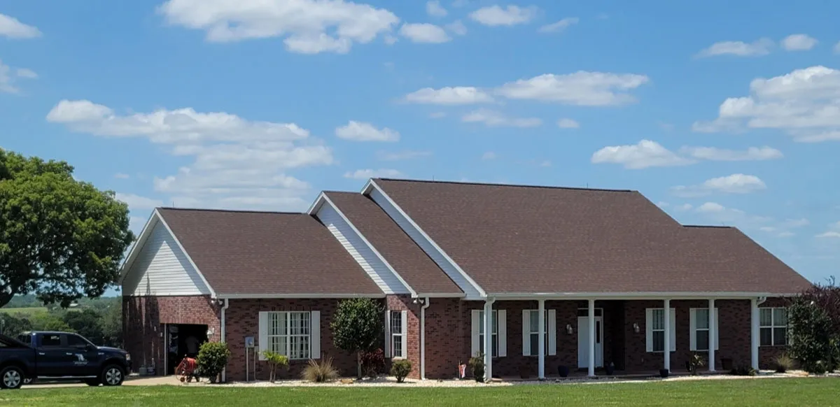 Completed brick ranch-style home with new shingle roof, covered porch, and landscaped yard by Florida building contractor
