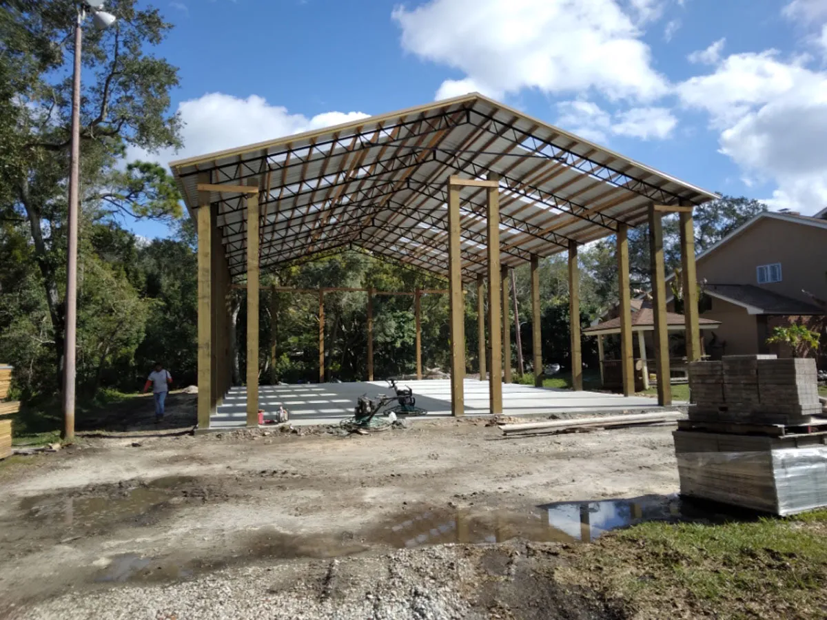Steel-framed pole barn with wood support columns and concrete foundation being constructed by Florida building contractor