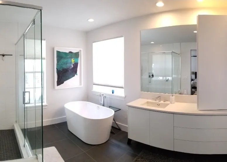 Modern bathroom with white freestanding bathtub, glass shower enclosure, large mirror, and white vanity.
