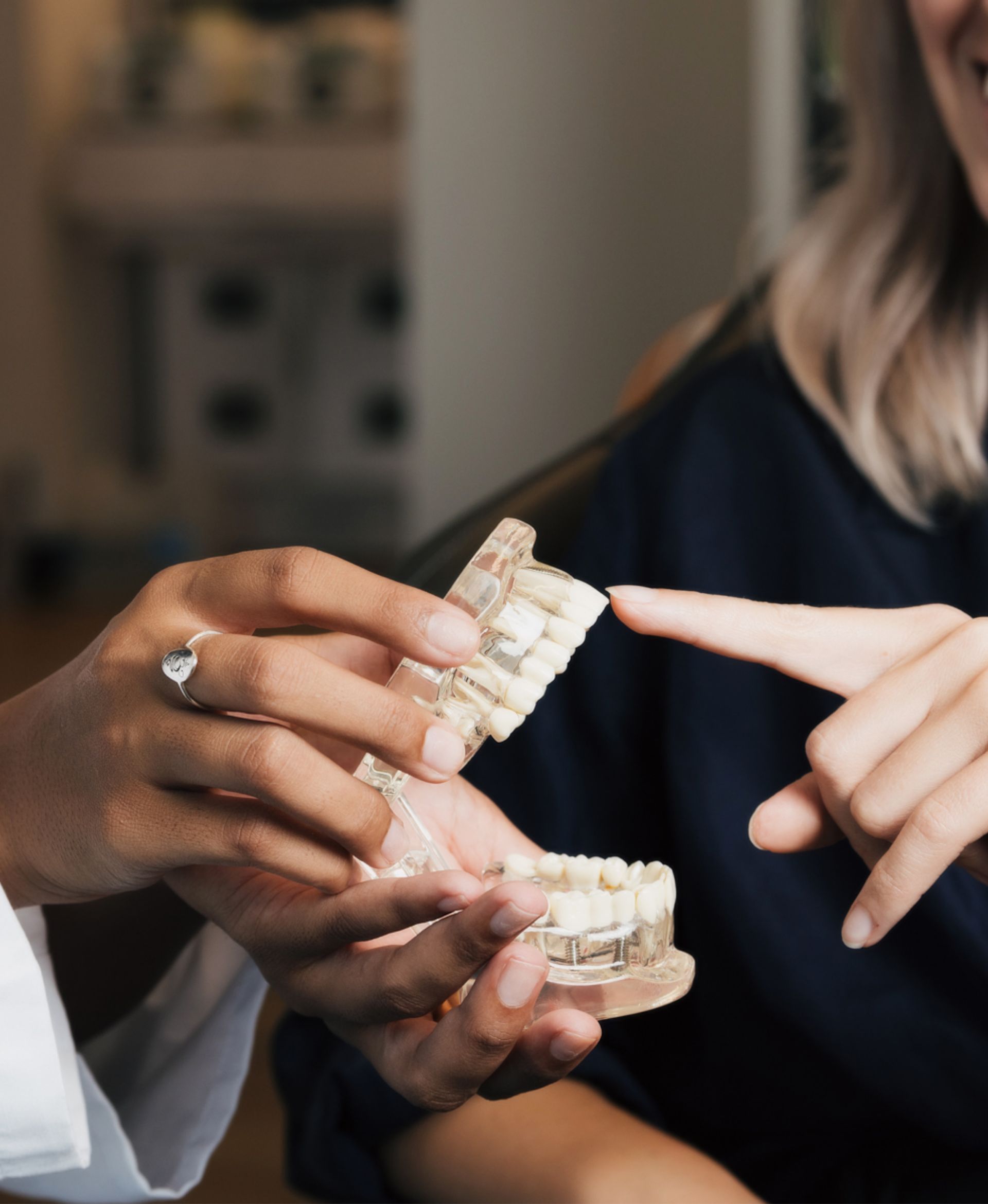 Person holding dental model while another person points at upper teeth on the model.