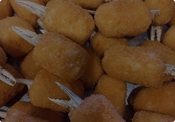 Close-up van meerdere goudbruine tapas-kroketten met kleine kreeftenklauwen, typische tapashapjes.