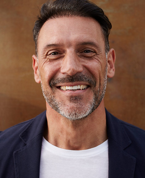 Team member portrait (Daniel Weber): Smiling professional man in natural light setting.