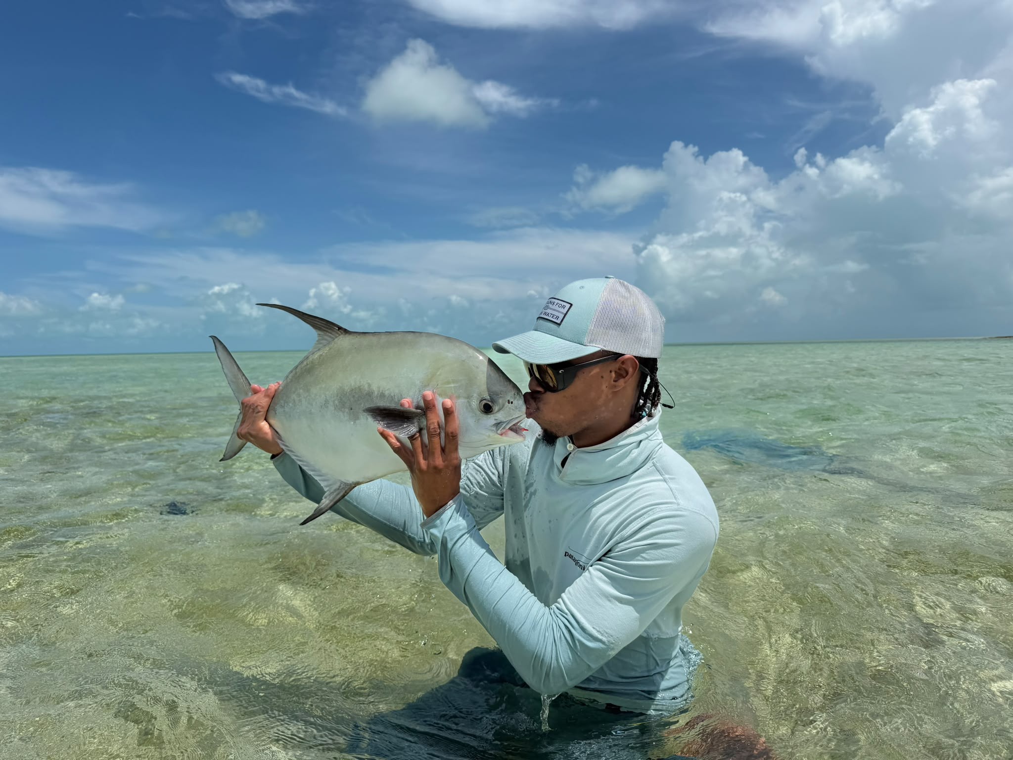 Soul Fly Lodge guide LJ Bean kissing a permit while wading a Berry Islands flat