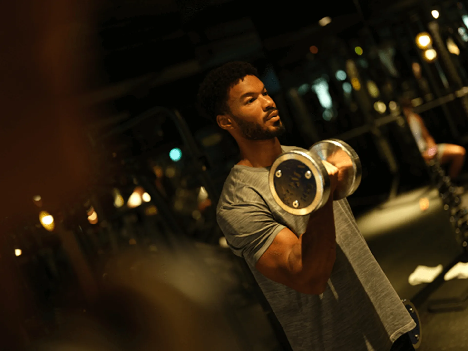 Man lifting a dumbbell in a dimly lit gym.