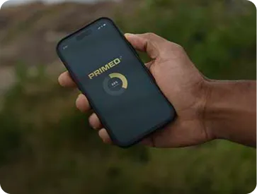 Hand holding a smartphone displaying the PRIMED app loading screen.