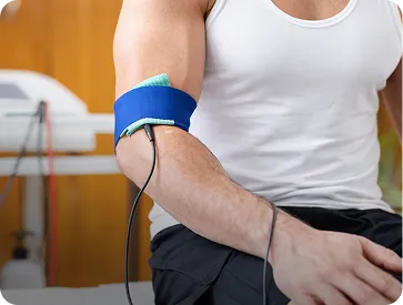 Person’s arm with a blue blood pressure cuff wrapped around the bicep during a health check.
