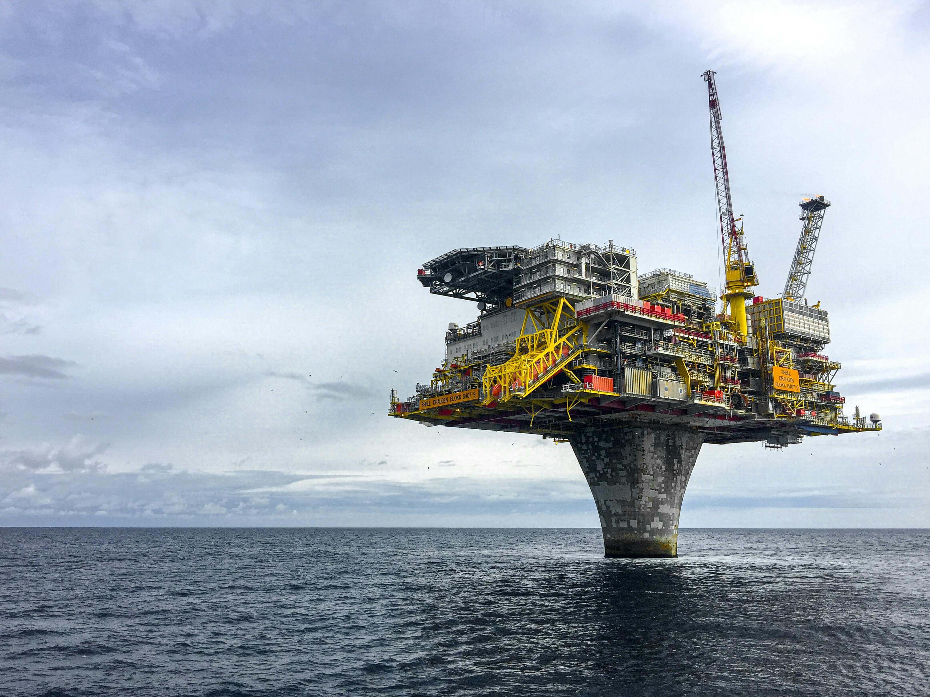 Offshore oil platform standing in the ocean under a cloudy sky.