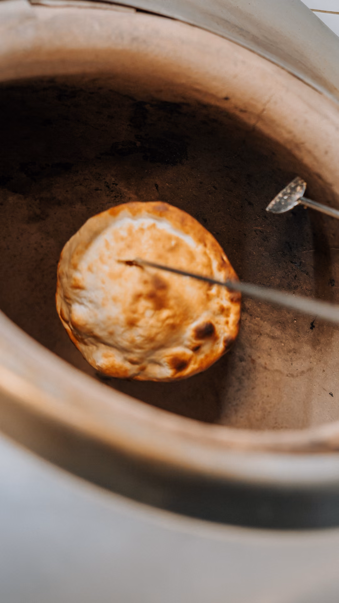 Naan bread cooking inside a tandoor oven