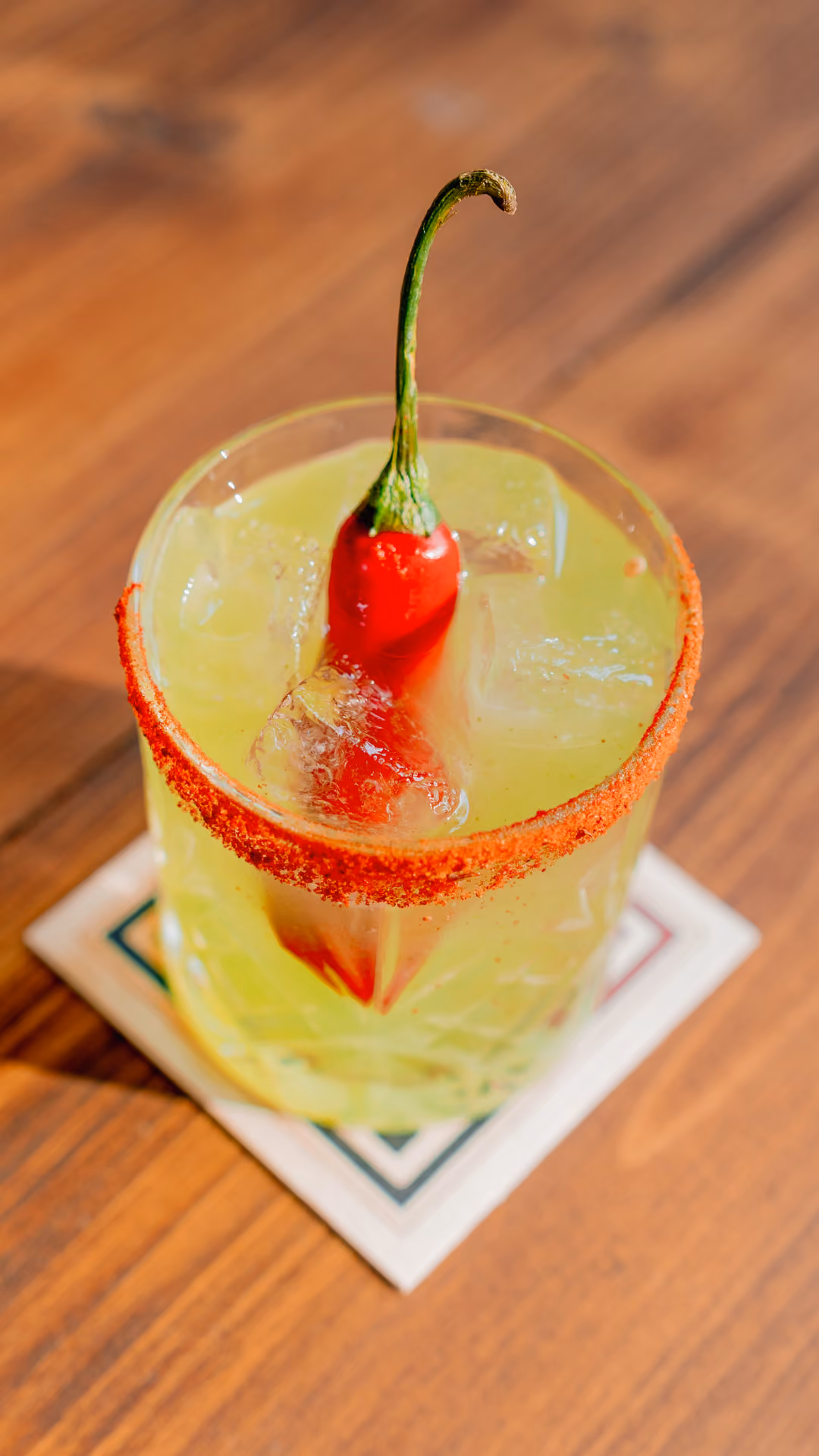 Green cocktail garnished with a red chilli