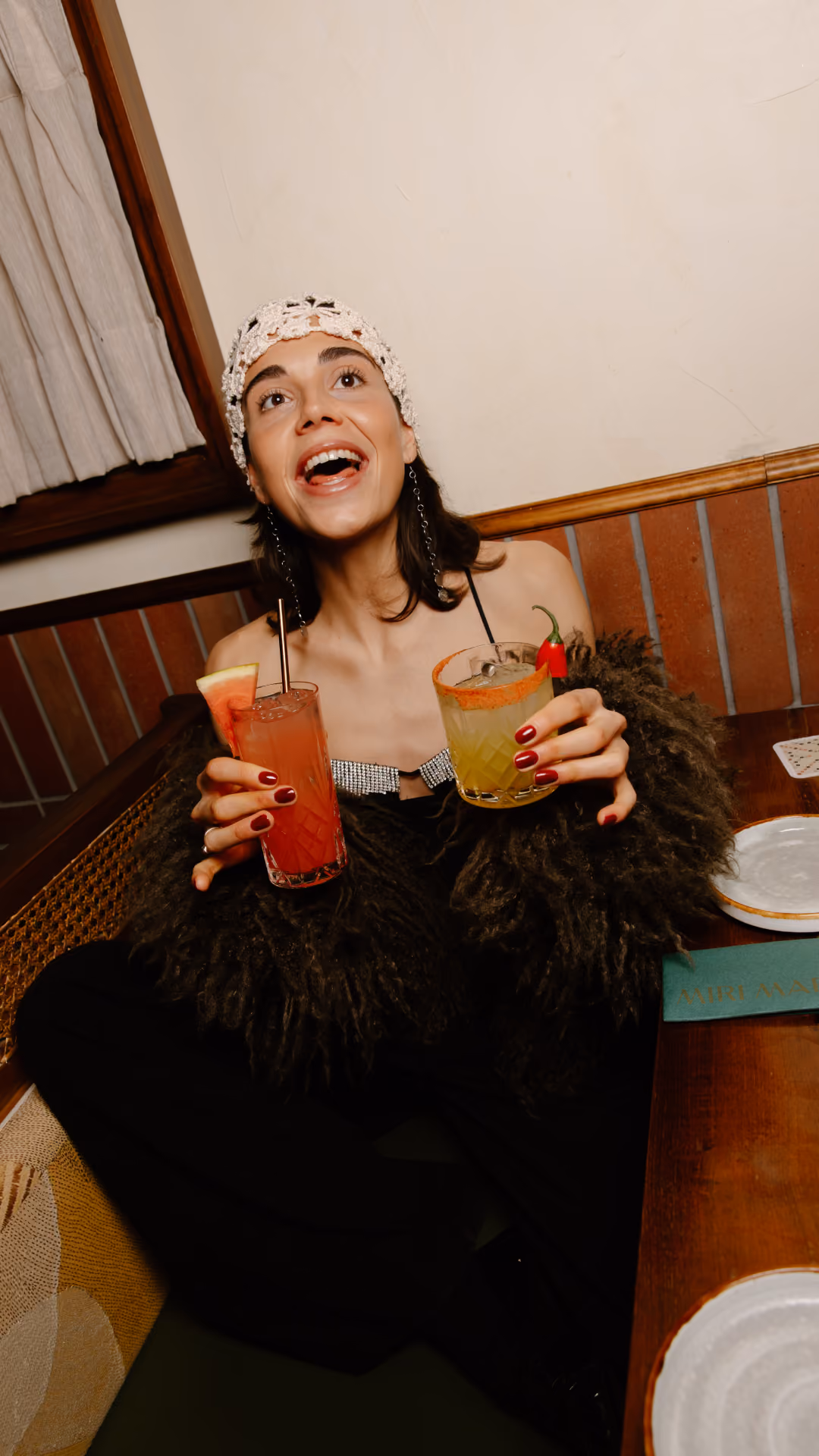 Guest holding two colourful cocktails at Miri Mary